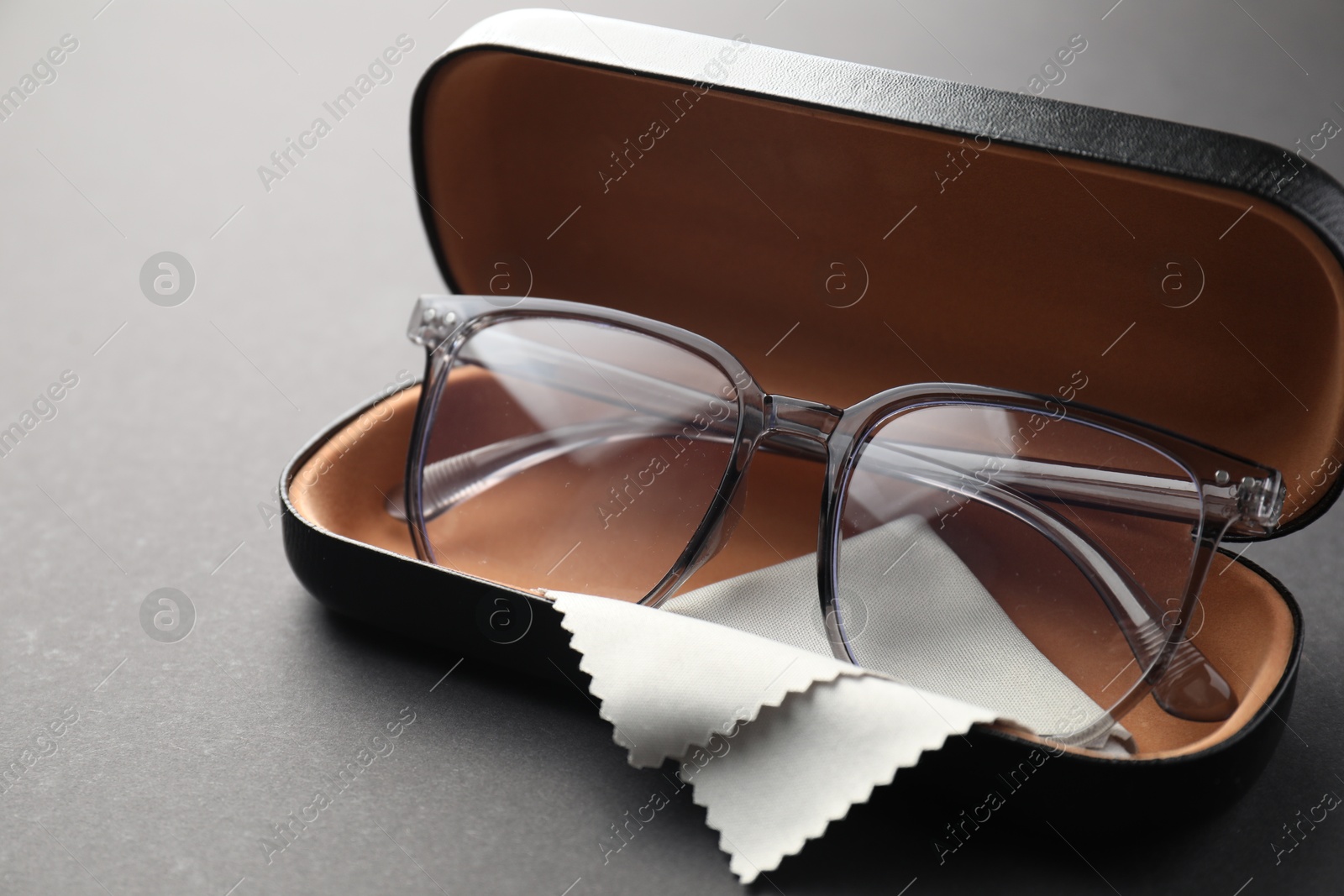 Case with stylish glasses and cleaning cloth on gray background, closeup Photo of Case with stylish glasses and cleaning cloth on gray background, closeup