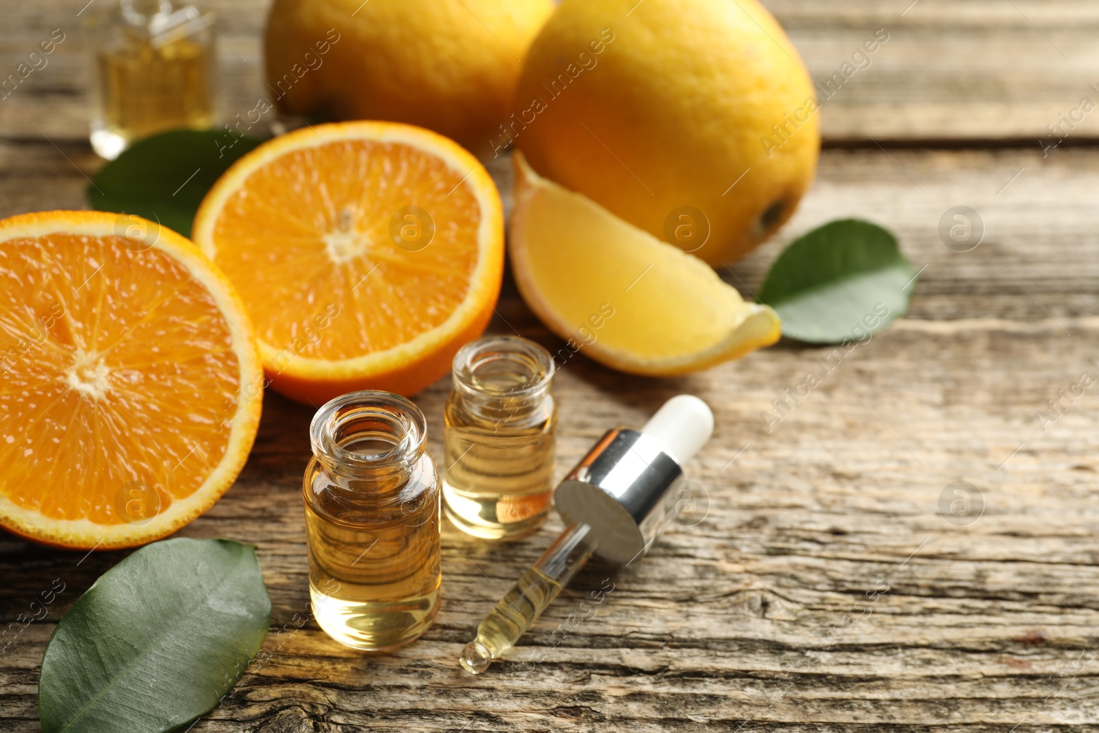 Open perfume bottles with aromatic essential oils, pipette, oranges and leaves on wooden table, closeup Photo of Open perfume bottles with aromatic essential oils, pipette, oranges and leaves on wooden table, closeup