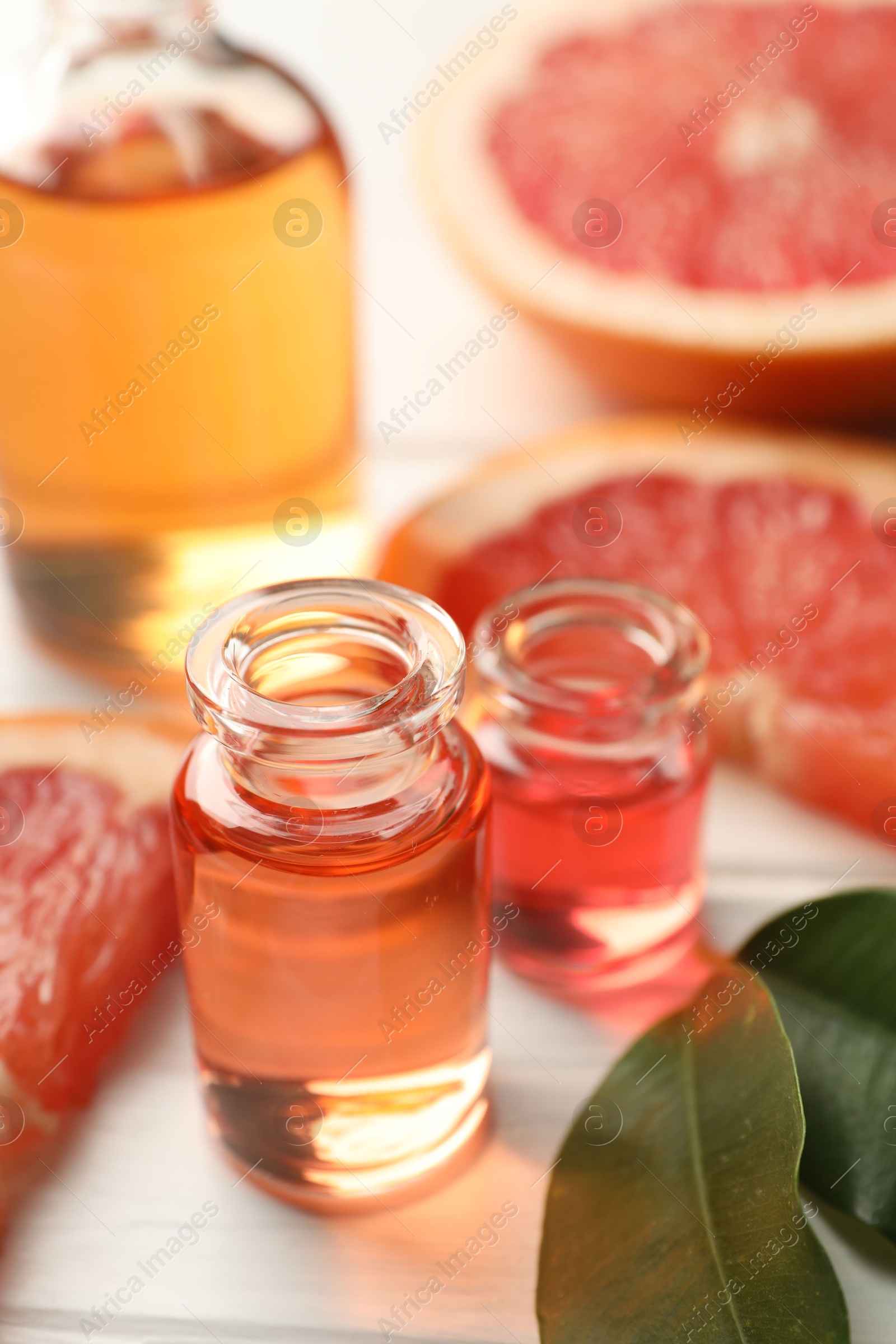 Open perfume bottles with aromatic essential oils, leaves and slices of grapefruit on white wooden table, closeup Photo of Open perfume bottles with aromatic essential oils, leaves and slices of grapefruit on white wooden table, closeup