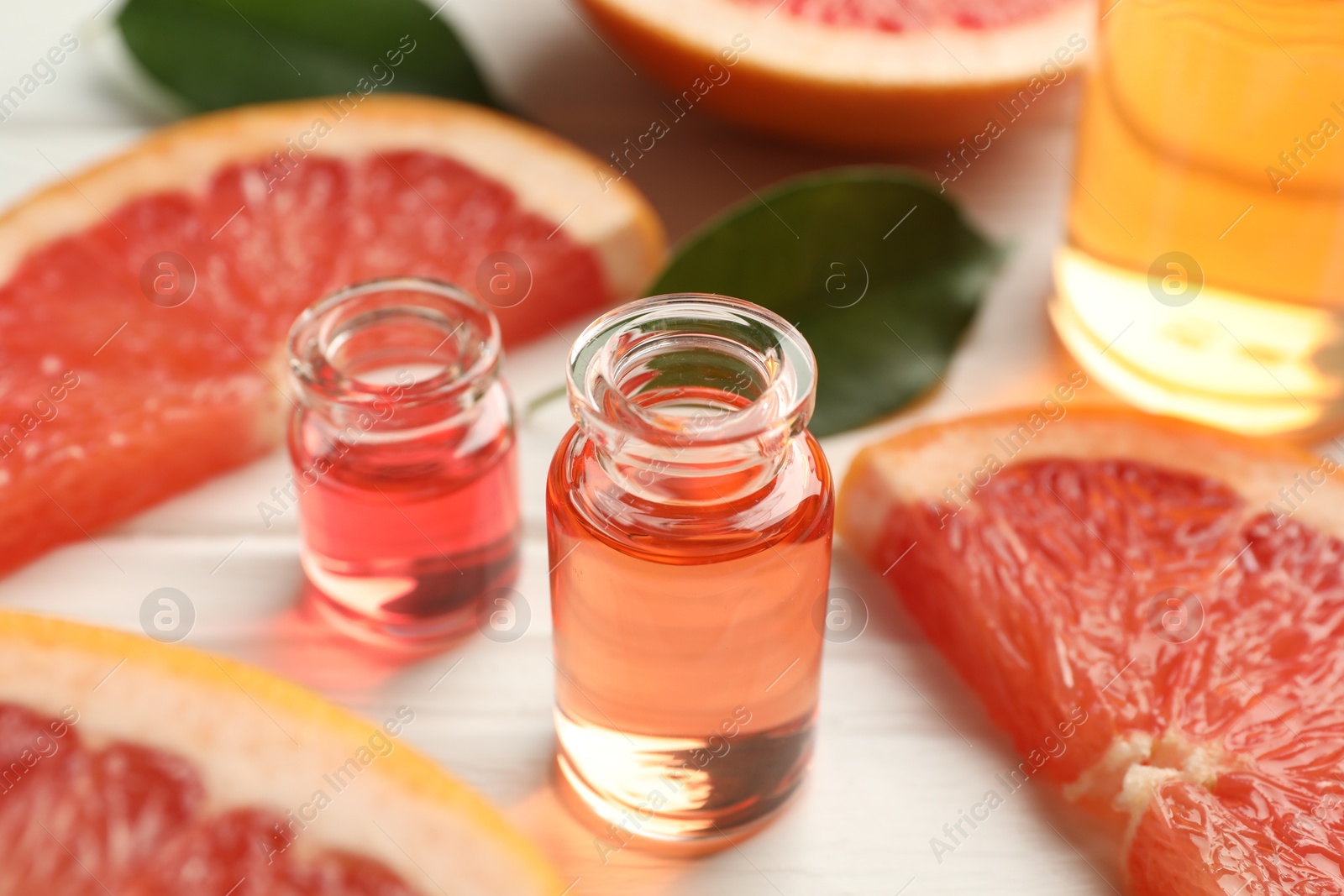 Open perfume bottles with aromatic essential oils and slices of grapefruit on white wooden table, closeup Photo of Open perfume bottles with aromatic essential oils and slices of grapefruit on white wooden table, closeup