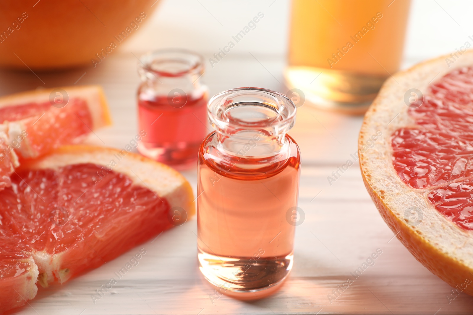 Open perfume bottles with aromatic essential oils and slices of grapefruit on white wooden table, closeup Photo of Open perfume bottles with aromatic essential oils and slices of grapefruit on white wooden table, closeup