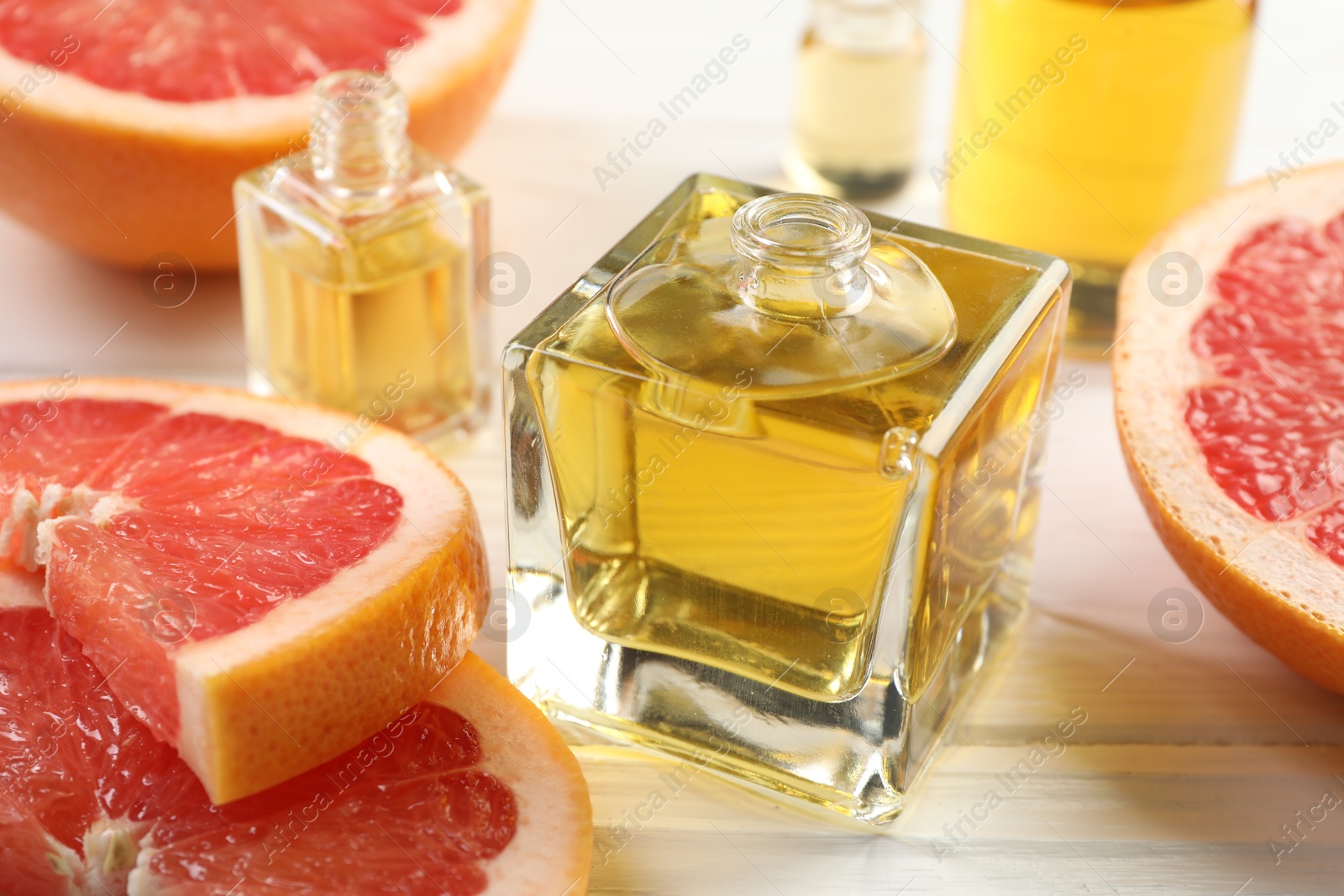 Open perfume bottles with aromatic essential oils and slices of grapefruit on white wooden table, closeup Photo of Open perfume bottles with aromatic essential oils and slices of grapefruit on white wooden table, closeup