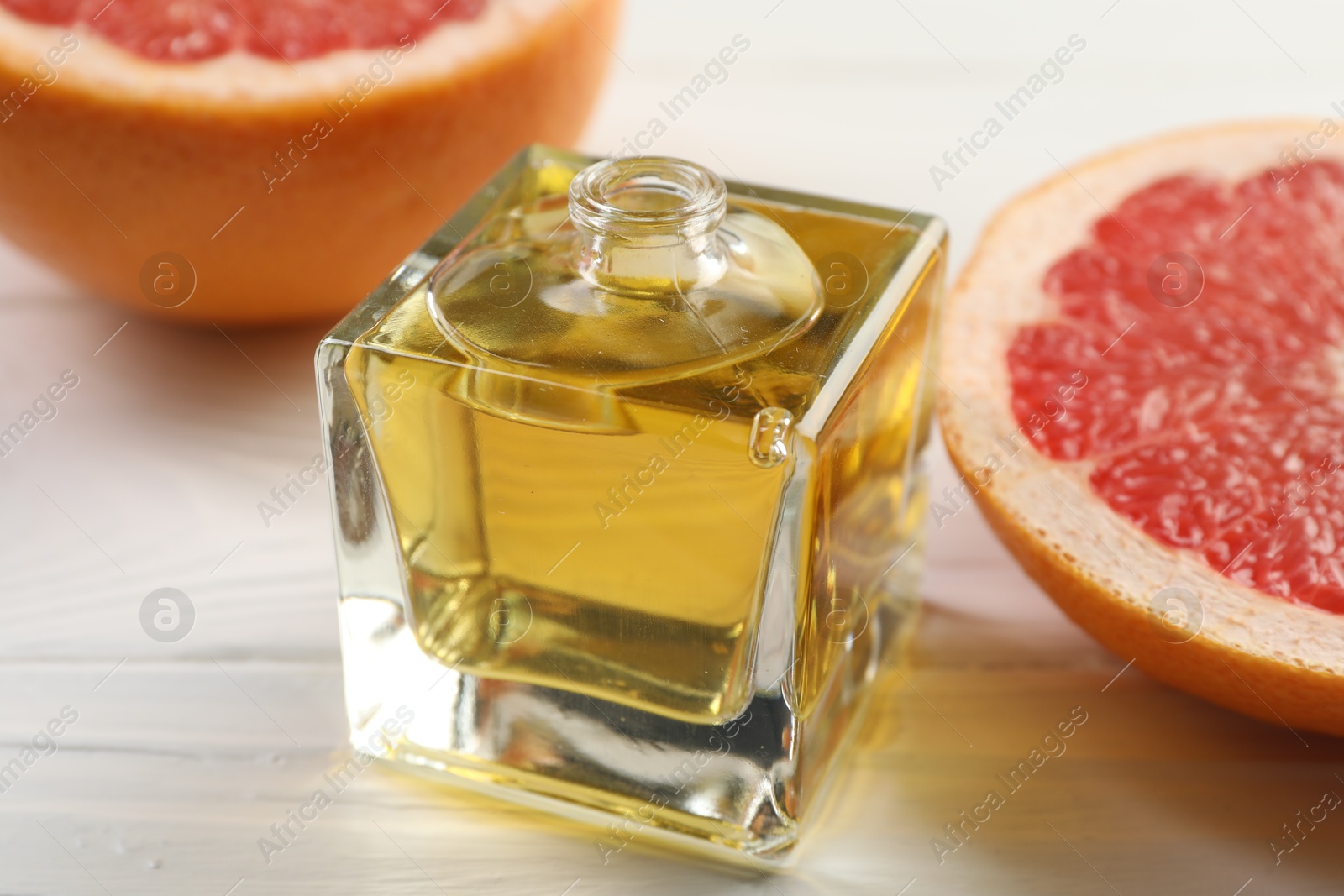 Open perfume bottle with aromatic essential oil and slices of grapefruit on white wooden table, closeup Photo of Open perfume bottle with aromatic essential oil and slices of grapefruit on white wooden table, closeup