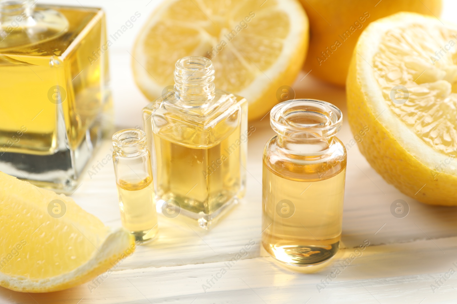 Open perfume bottles with aromatic essential oils and slices of lemons on white wooden table, closeup Photo of Open perfume bottles with aromatic essential oils and slices of lemons on white wooden table, closeup