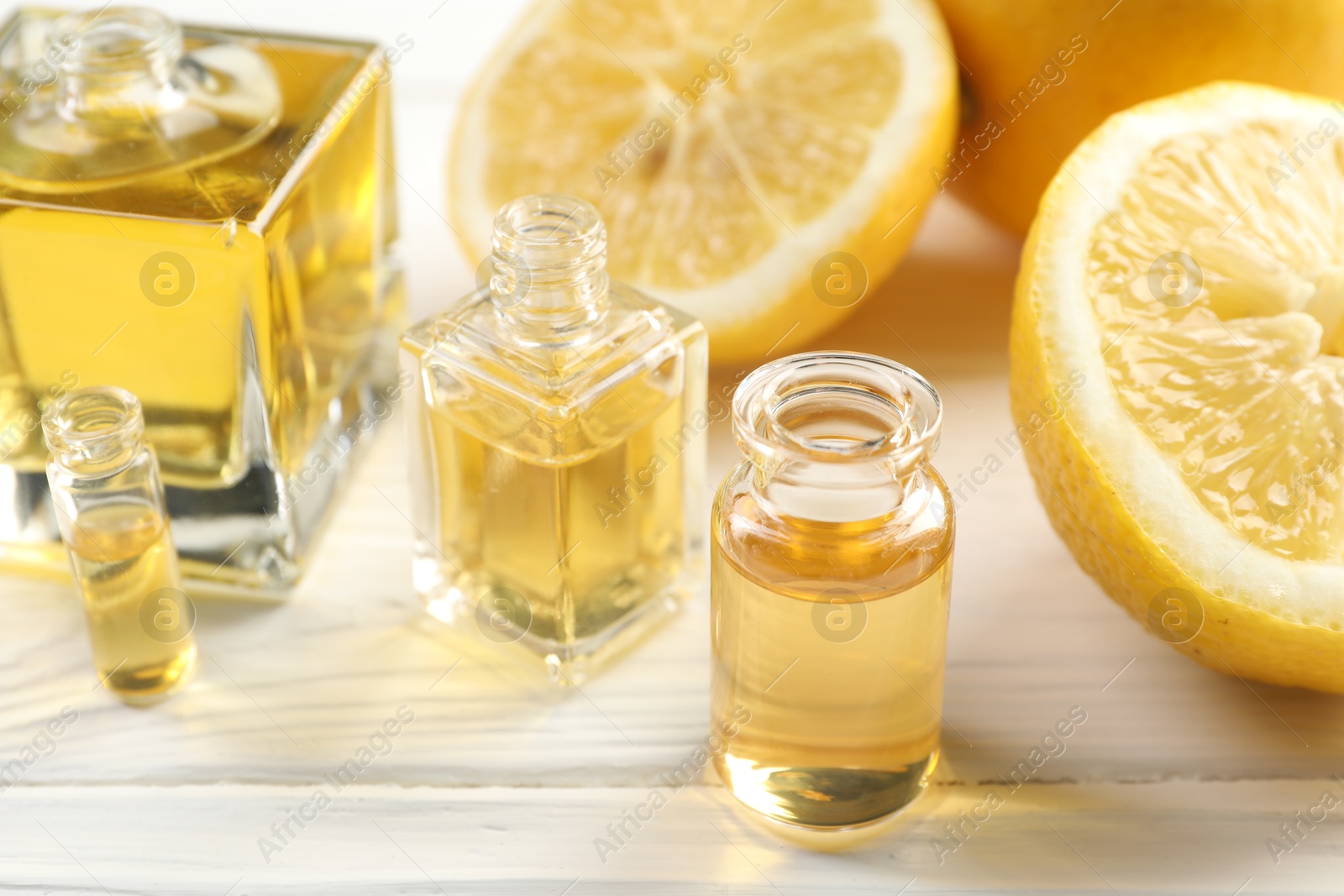 Open perfume bottles with aromatic essential oils and slices of lemons on white wooden table, closeup Photo of Open perfume bottles with aromatic essential oils and slices of lemons on white wooden table, closeup