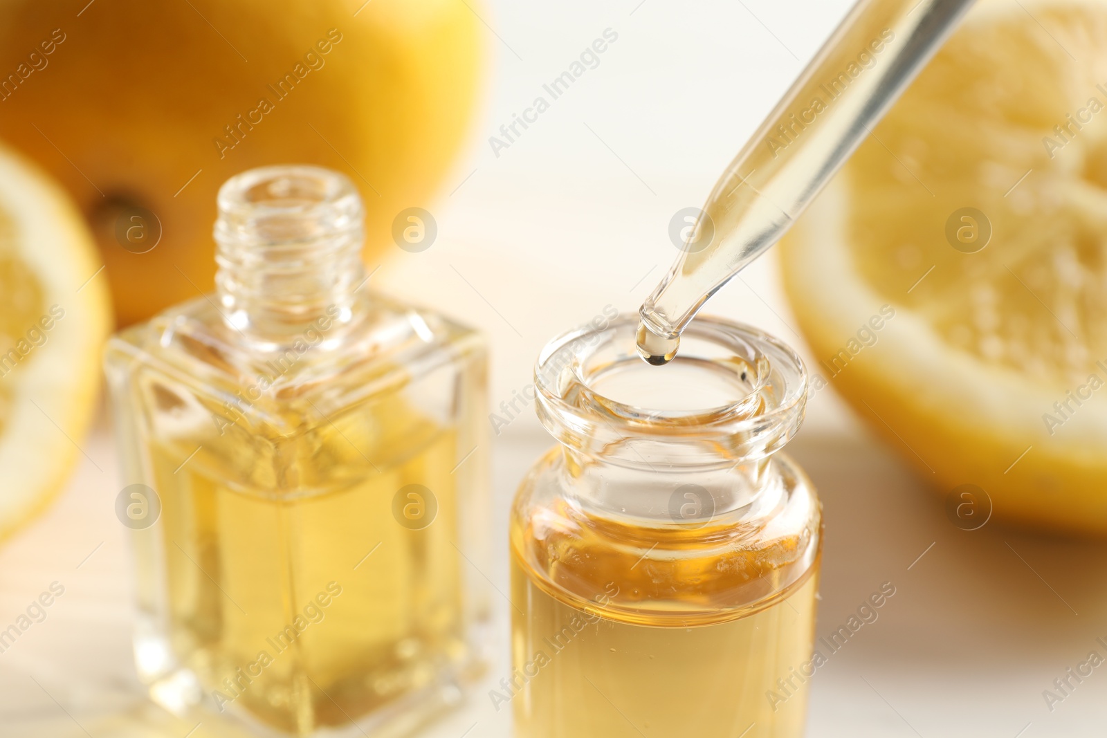 Dripping aromatic essential oil from pipette into perfume bottle at white table, closeup Photo of Dripping aromatic essential oil from pipette into perfume bottle at white table, closeup