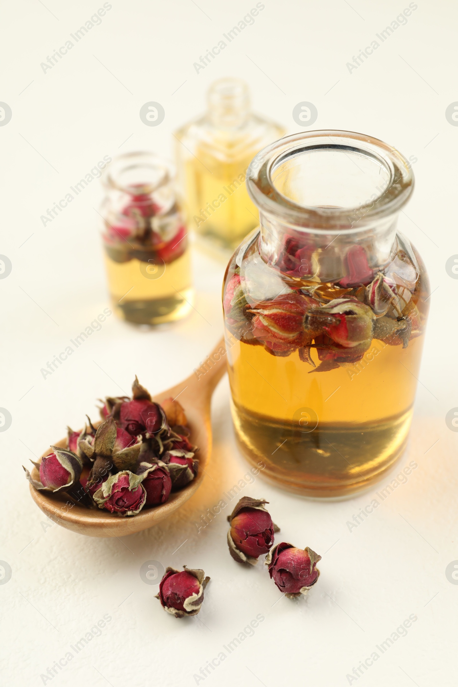 Open perfume bottles with aromatic essential oils and dried roses on white table, closeup Photo of Open perfume bottles with aromatic essential oils and dried roses on white table, closeup