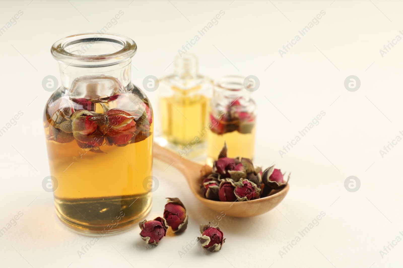 Open perfume bottles with aromatic essential oils and dried roses on white table, closeup. Space for text Photo of Open perfume bottles with aromatic essential oils and dried roses on white table, closeup. Space for text