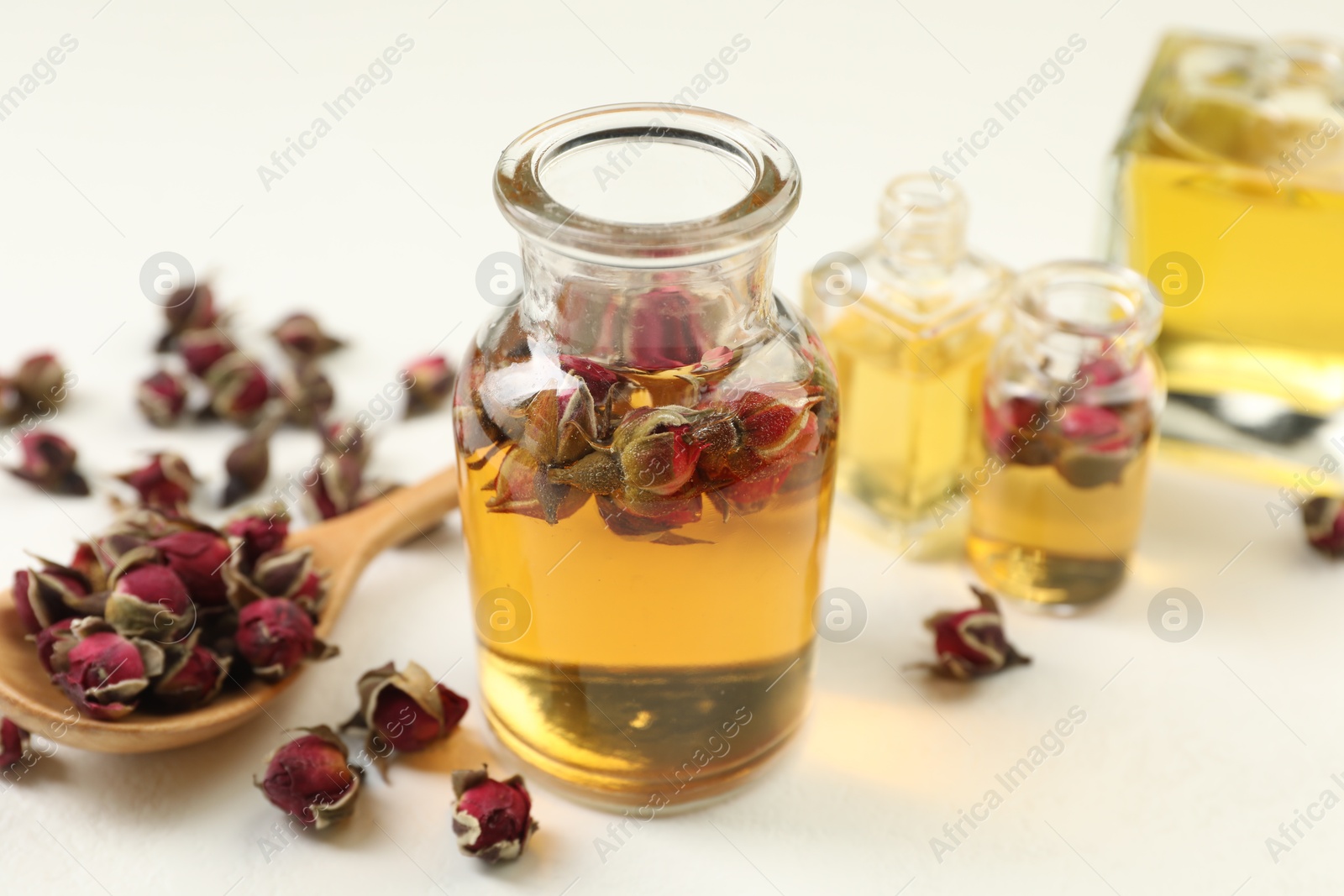 Open perfume bottles with aromatic essential oils and dried roses on white table, closeup Photo of Open perfume bottles with aromatic essential oils and dried roses on white table, closeup