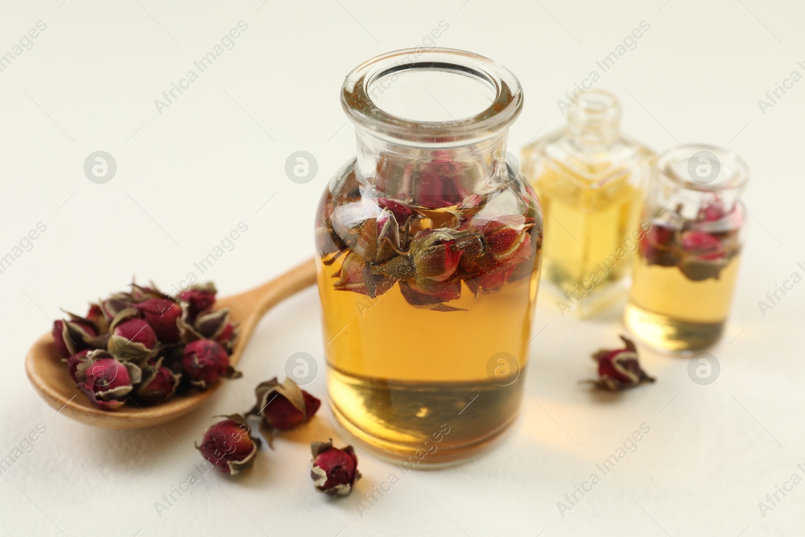 Open perfume bottles with aromatic essential oils and dried roses on white table, closeup Photo of Open perfume bottles with aromatic essential oils and dried roses on white table, closeup