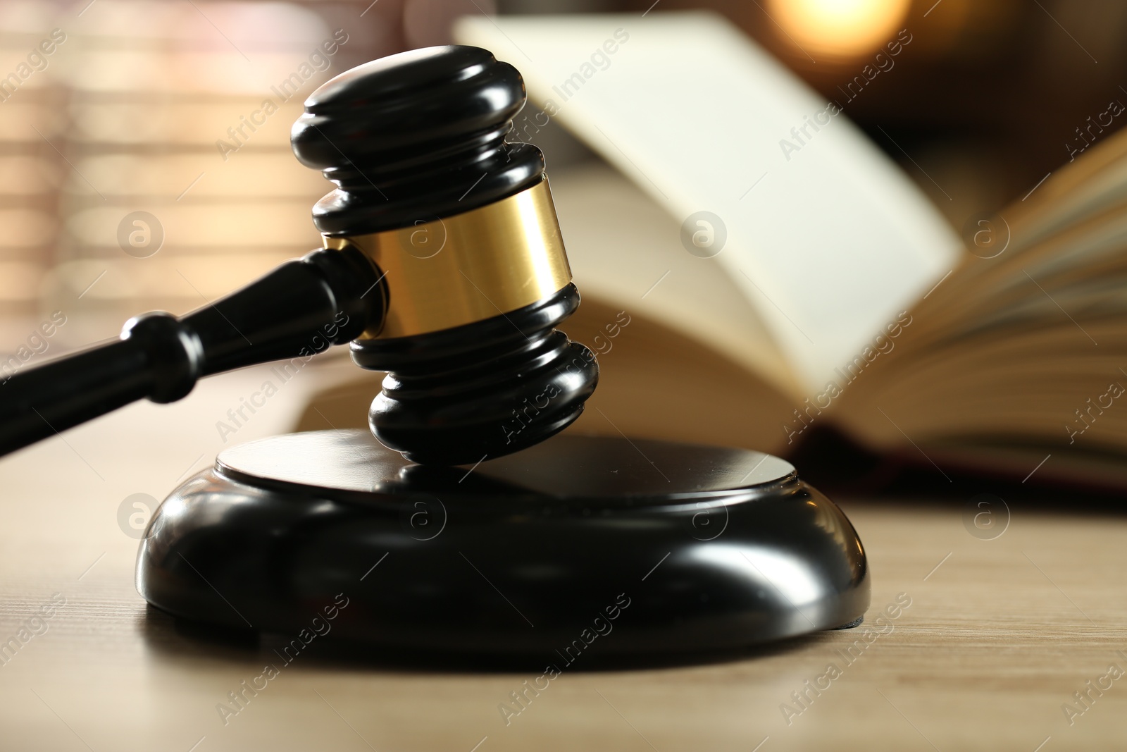 Photo of Judge's gavel and book on wooden table indoors, selective focus