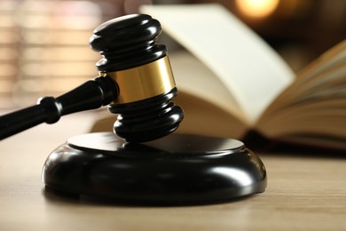 Photo of Judge's gavel and book on wooden table indoors, selective focus
