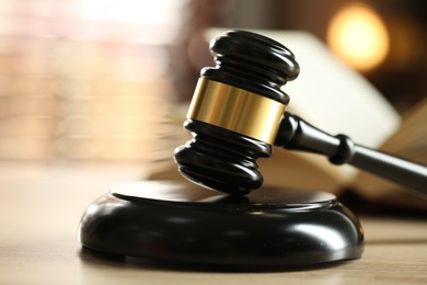 Photo of Judge's gavel and book on wooden table indoors, selective focus