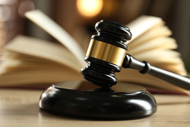 Photo of Judge's gavel and book on wooden table indoors, selective focus