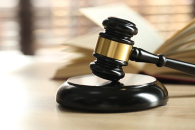 Photo of Judge's gavel and book on wooden table indoors, selective focus