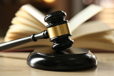 Photo of Judge's gavel and book on wooden table indoors, selective focus