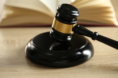 Photo of Judge's gavel and book on wooden table indoors, selective focus