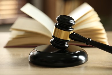 Photo of Judge's gavel and book on wooden table indoors, selective focus