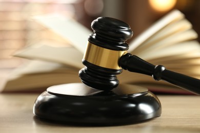 Photo of Judge's gavel and book on wooden table indoors, selective focus