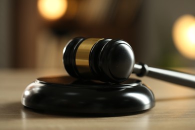 Photo of Judge's gavel on wooden table against blurred background, closeup