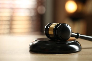 Photo of Judge's gavel on wooden table against blurred background, closeup