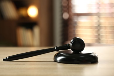 Photo of Judge's gavel on wooden table against blurred background, closeup
