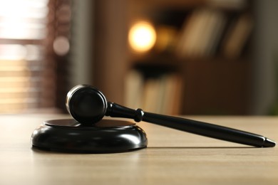 Photo of Judge's gavel on wooden table against blurred background, closeup