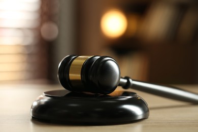 Photo of Judge's gavel on wooden table against blurred background, closeup