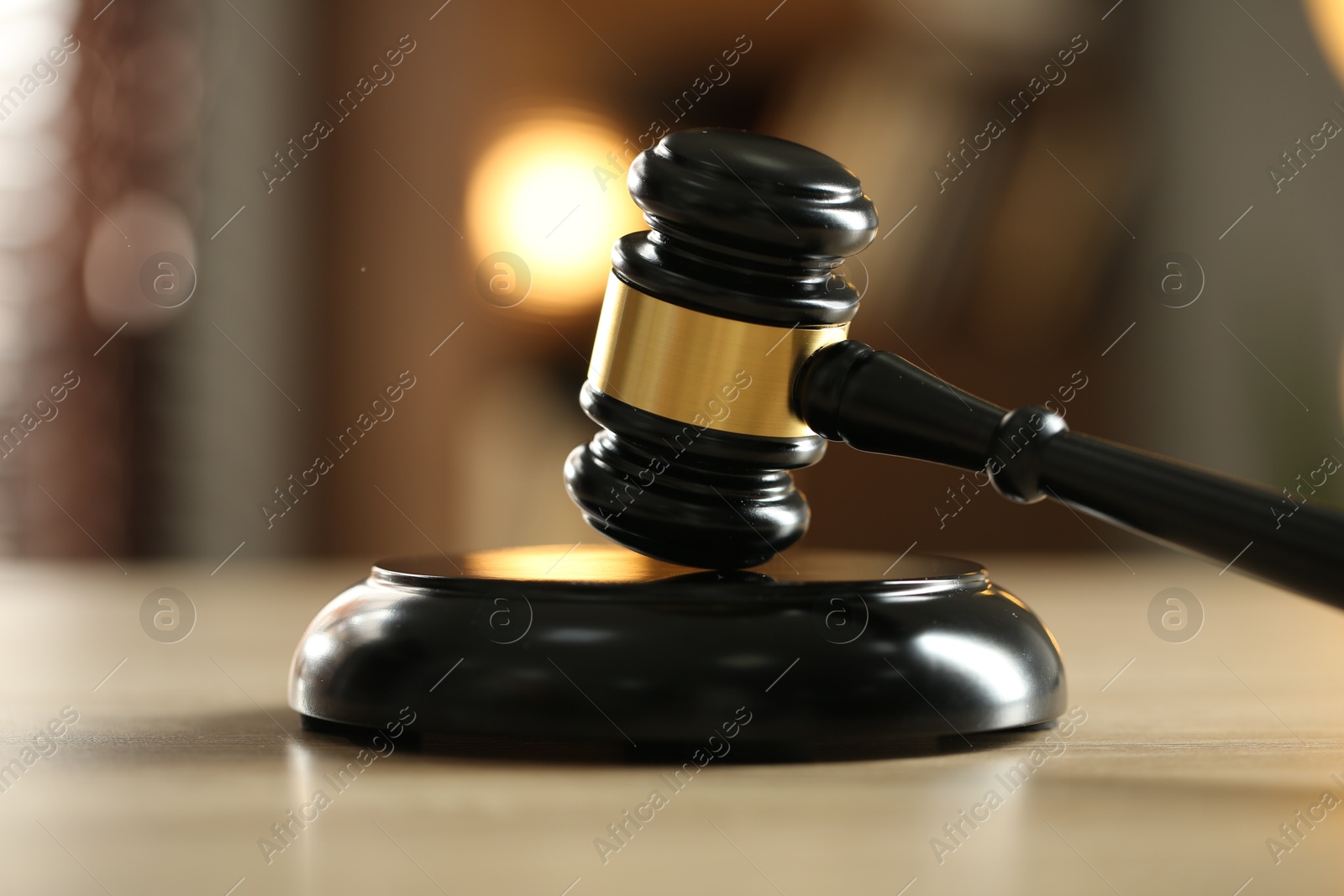 Photo of Judge's gavel on wooden table against blurred background, closeup