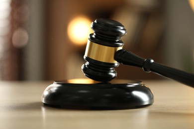 Photo of Judge's gavel on wooden table against blurred background, closeup