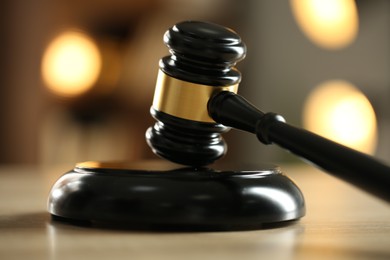Photo of Judge's gavel on wooden table against blurred background, closeup