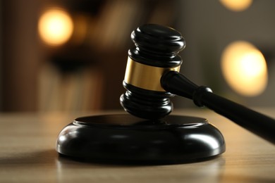 Photo of Judge's gavel on wooden table against blurred background, closeup