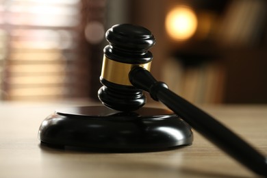 Photo of Judge's gavel on wooden table against blurred background, closeup