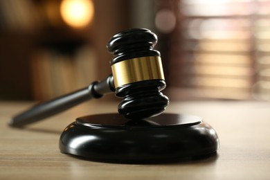 Photo of Judge's gavel on wooden table against blurred background, closeup