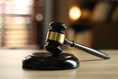 Photo of Judge's gavel on wooden table against blurred background, closeup