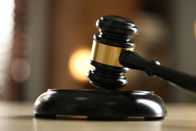Photo of Judge's gavel on wooden table against blurred background, closeup