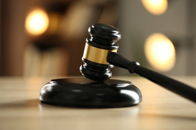 Photo of Judge's gavel on wooden table against blurred background, closeup