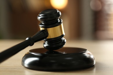 Photo of Judge's gavel on wooden table against blurred background, closeup