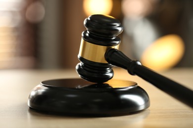 Photo of Judge's gavel on wooden table against blurred background, closeup