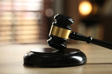Photo of Judge's gavel on wooden table against blurred background, closeup