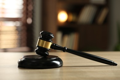 Photo of Judge's gavel on wooden table against blurred background, closeup