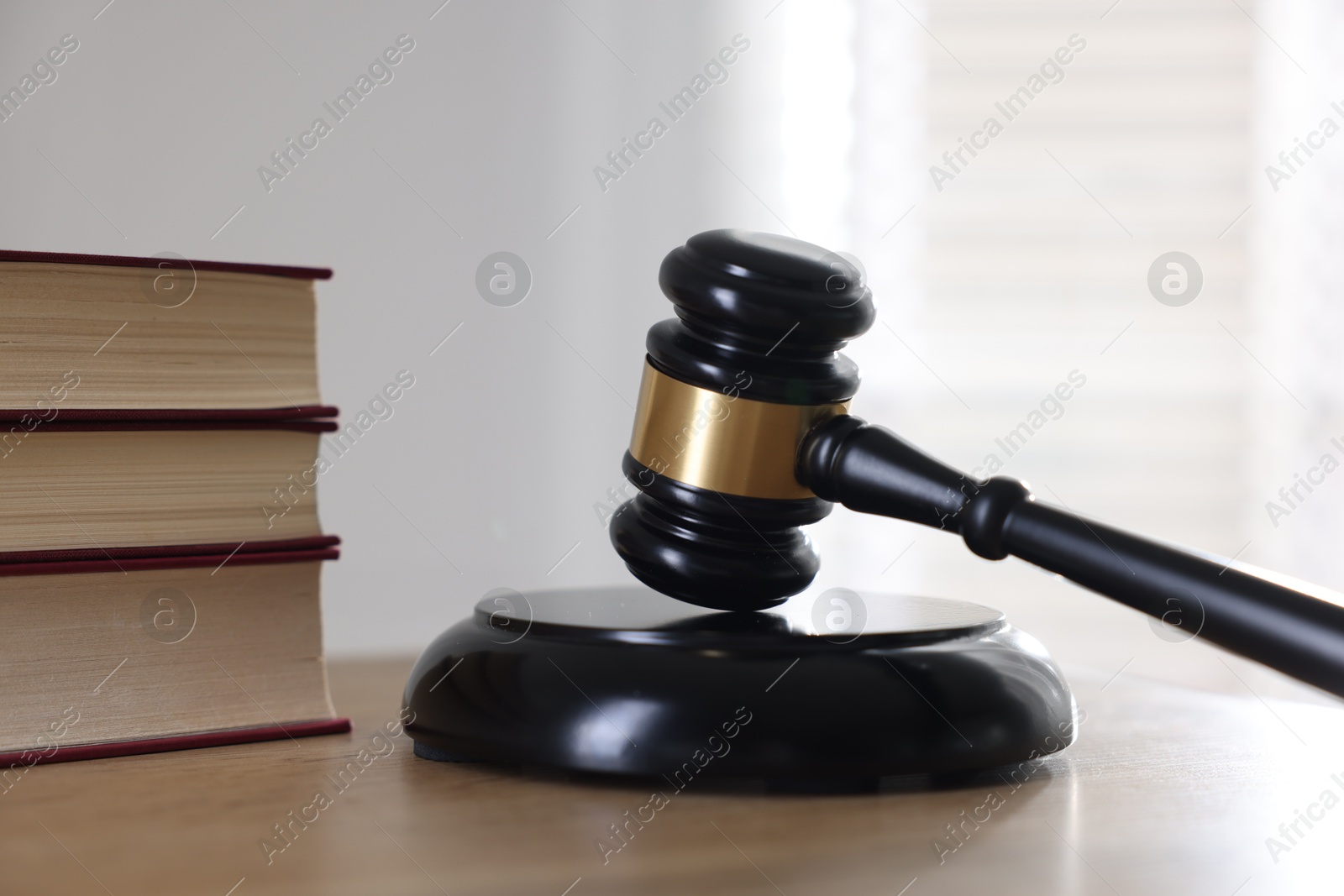 Photo of Judge's gavel and books on wooden table indoors, closeup