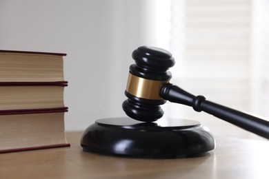 Photo of Judge's gavel and books on wooden table indoors, closeup