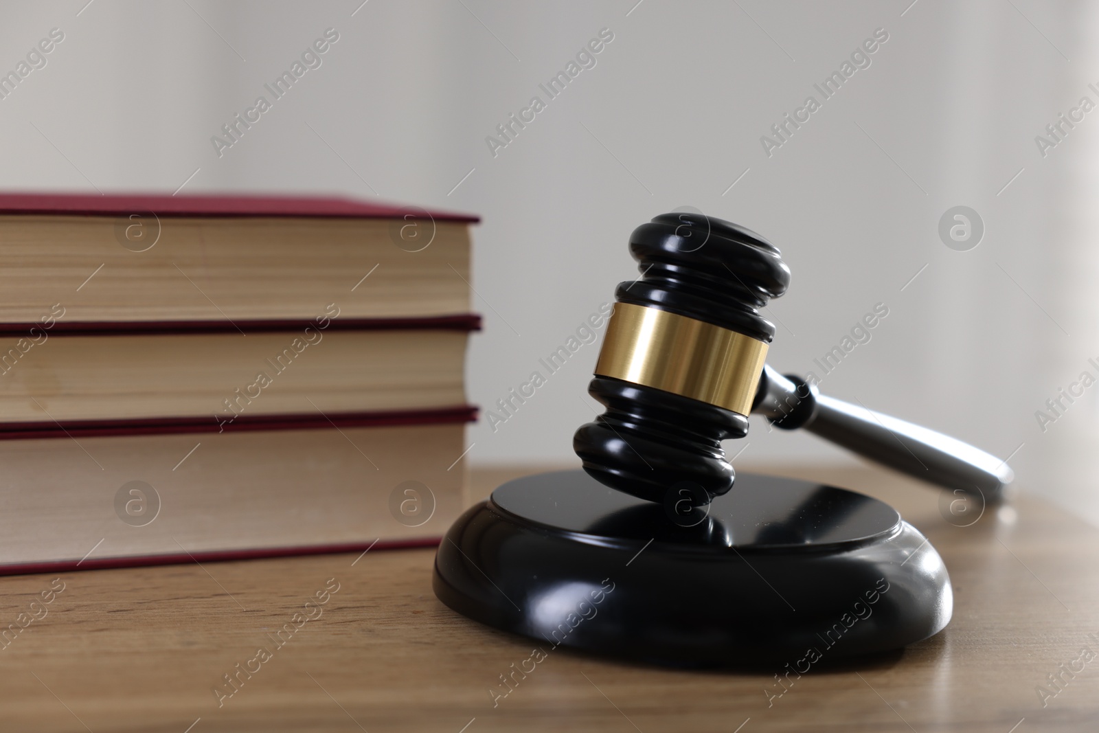 Photo of Judge's gavel and books on wooden table indoors, closeup