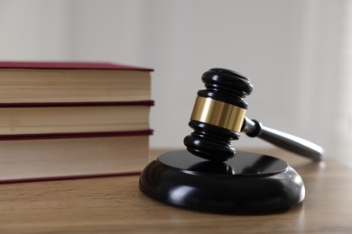 Photo of Judge's gavel and books on wooden table indoors, closeup