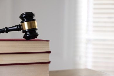 Photo of Judge's gavel and books on table indoors, closeup