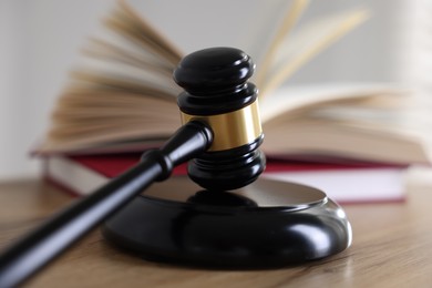 Photo of Judge's gavel and books on wooden table indoors, selective focus