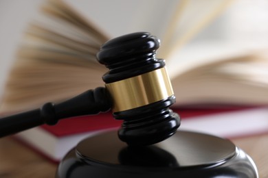 Photo of Judge's gavel and books on wooden table indoors, selective focus