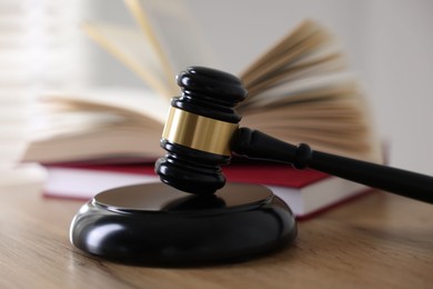 Photo of Judge's gavel and books on wooden table indoors, selective focus