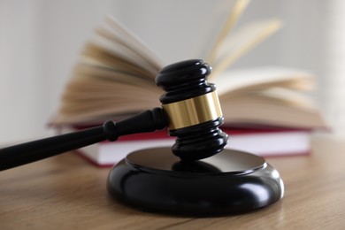 Photo of Judge's gavel and books on wooden table indoors, selective focus